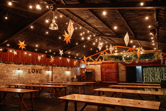 Barn decorated with stars and fairy lights with picnic-style tables